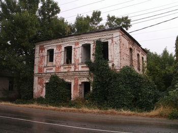 Abandoned building by road against trees