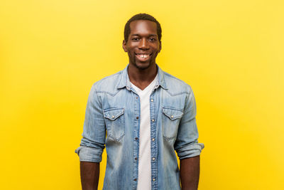 Portrait of smiling young man against yellow background