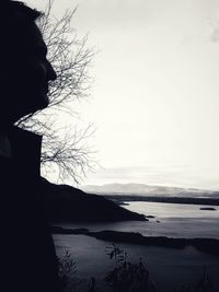 Silhouette woman looking at lake against sky