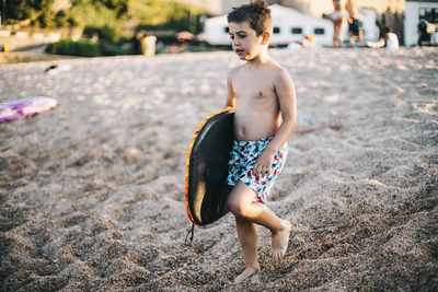 Full length of shirtless boy lying on land