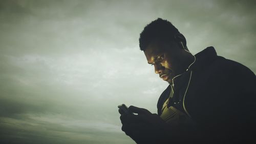 Man using smart phone against sky