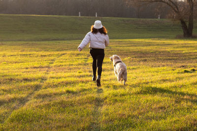 Rear view of man with dog on field