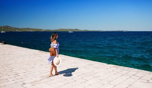 Full length of woman standing on pier against clear sky