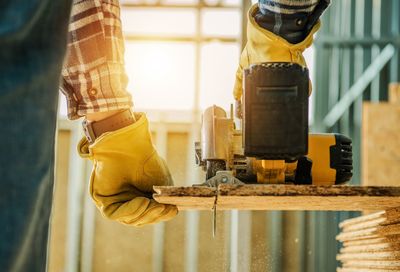 Cropped image of man cutting wood in workshop