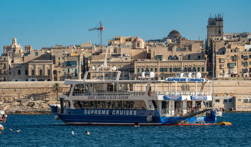 Sailboats in sea against buildings in city