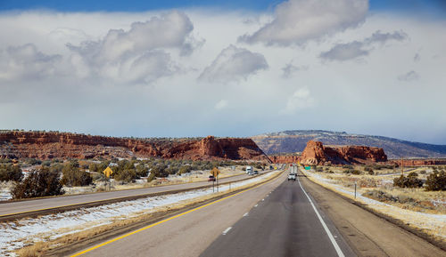 Empty road along landscape against sky