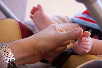 Cropped image of father touching baby foot on bed at home
