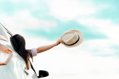 Rear view of woman photographing car against sky