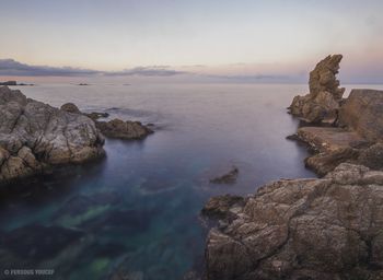 Rock formation on sea against sky during sunset