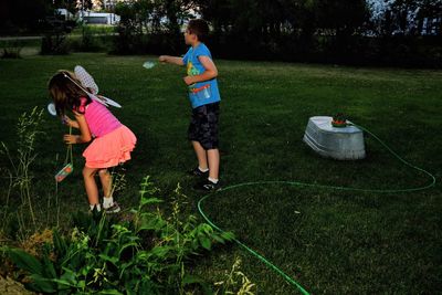 Siblings playing on field in yard