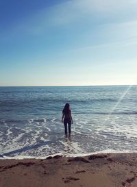 Rear view of woman on beach against sky