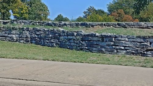 Stack of stone wall by trees against sky