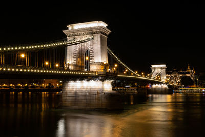 Illuminated bridge over river at night