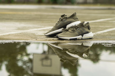 Close-up of shoes by puddle on road