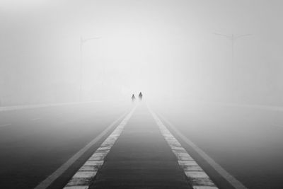 Rear view of people walking on road in fog