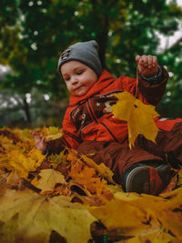 Portrait of cute boy with leaves during autumn
