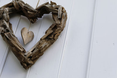Close-up of wooden heart shape hanging on white wall