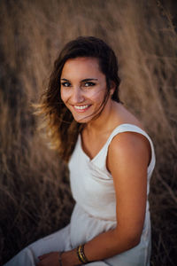 Portrait of young woman smiling while sitting on field