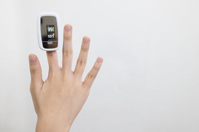 Close-up of hand holding telephone against white background