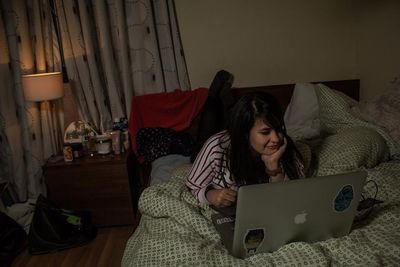 Woman lying on bed and using a laptop