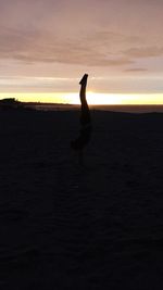 Silhouette man standing on field at sunset