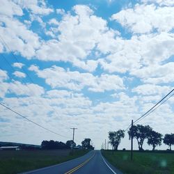 Empty country road against cloudy sky