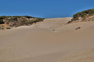 Sand dunes in desert against clear blue sky