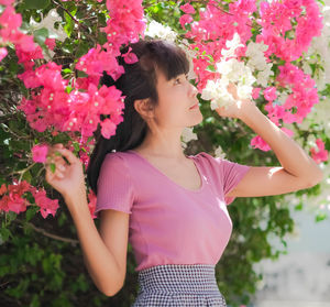 Midsection of woman standing by pink flowering plants