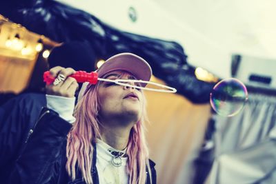 Close-up of woman blowing bubble while standing outdoors