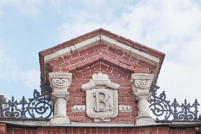 Monogram, first letter of name of russian merchant vasily gomulin, above gate of his estate of 1885