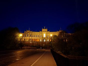 Illuminated buildings against blue sky at night