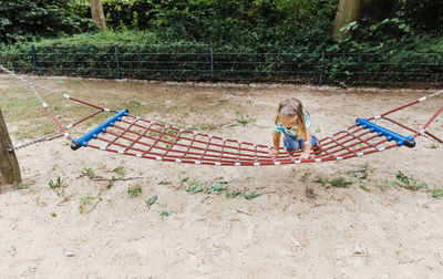 High angle view of girl sitting on hammock outdoors