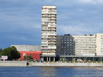 Buildings by river against sky in city