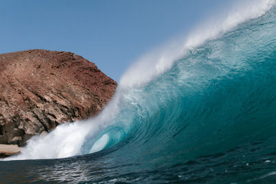 Blue wave breaking front a red mountain in tenerife