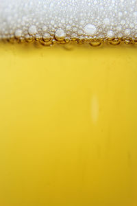 Close-up of yellow glass against orange background
