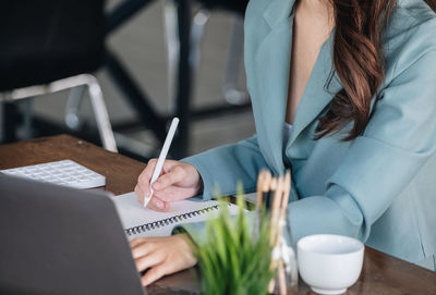 Midsection of woman using laptop on table