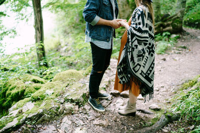 Low section of woman standing on ground in forest