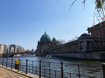 Bridge over river by buildings against sky in city