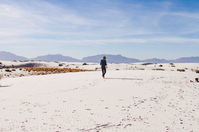 Rear view of man walking on sand at desert