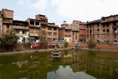 Buildings by lake against sky in city