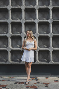 Full length of woman standing against brick wall