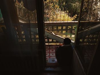 Rear view of man looking through window