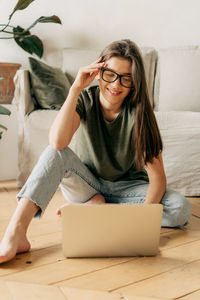 Young woman using mobile phone while sitting on table