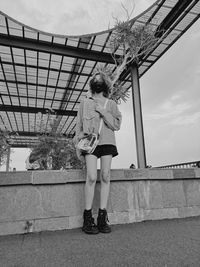 Full length of woman standing by railing against sky