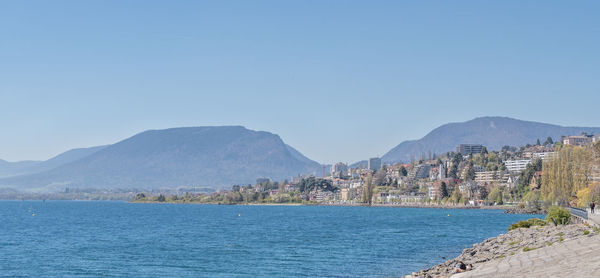 Scenic view of sea by buildings against clear blue sky