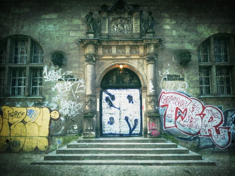 architecture, built structure, graffiti, building exterior, art, art and craft, creativity, human representation, text, door, wall - building feature, entrance, arch, street art, building, western script, day, mural, outdoors