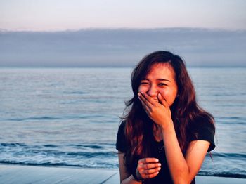 Beautiful young woman against sea against sky