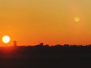 Silhouette landscape against orange sky