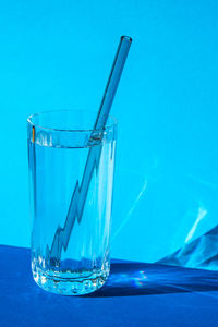 Reusable glass straws in glass with water on blue background eco-friendly drinking straw set with