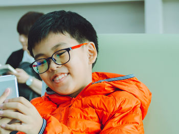Close-up of boy wearing eyeglasses using smart phone